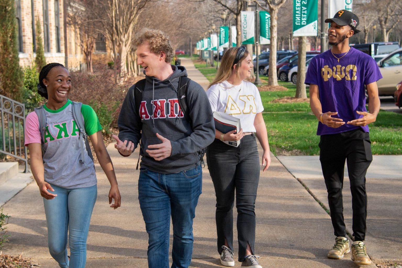 希腊的生活 students walking 和 engaging with each other on campus.